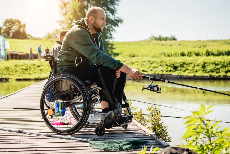 Young disabled man in a wheelchair fishing